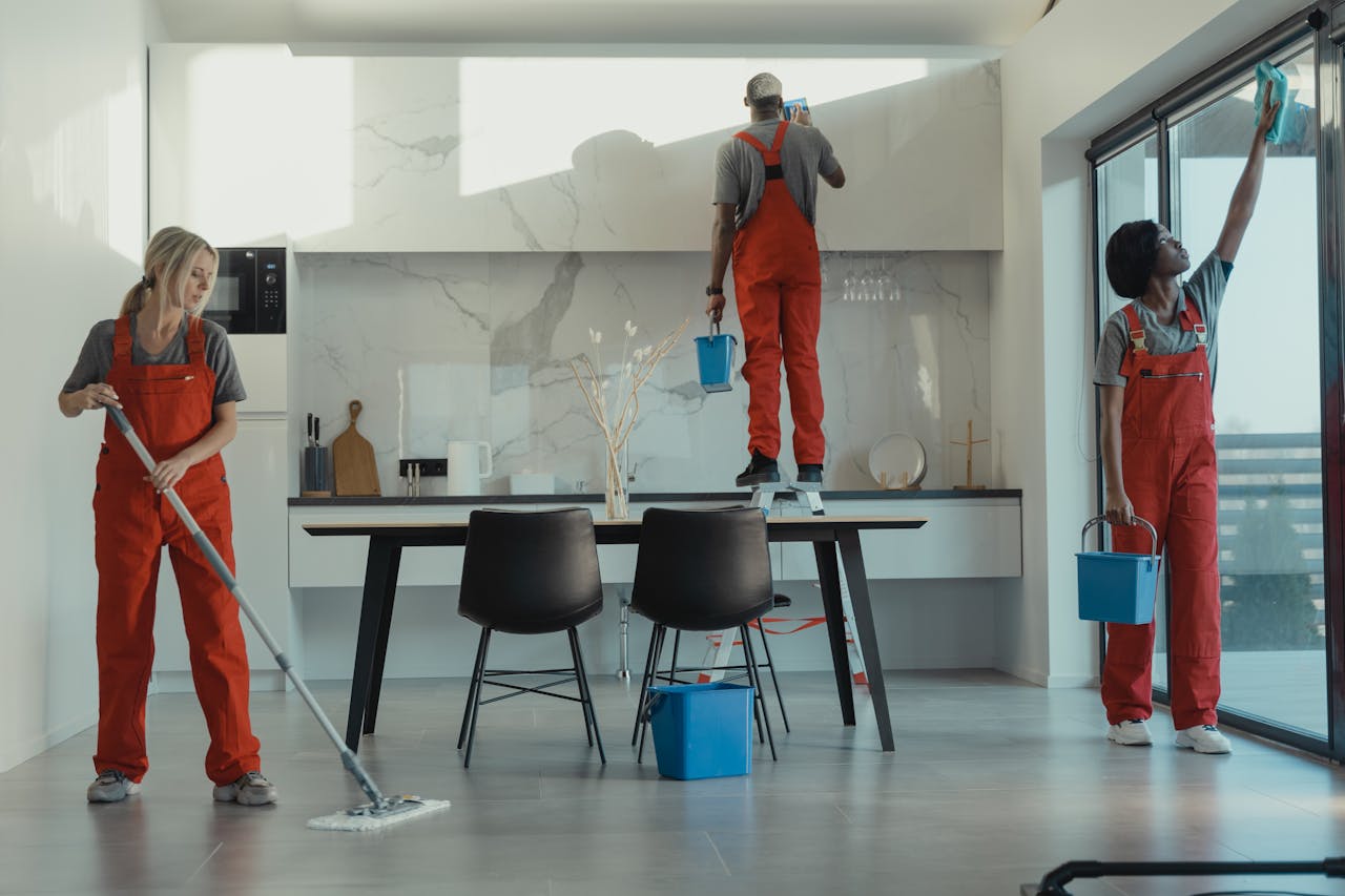 services-02 Group of cleaners in red uniforms mopping and wiping glass in a modern dining room.